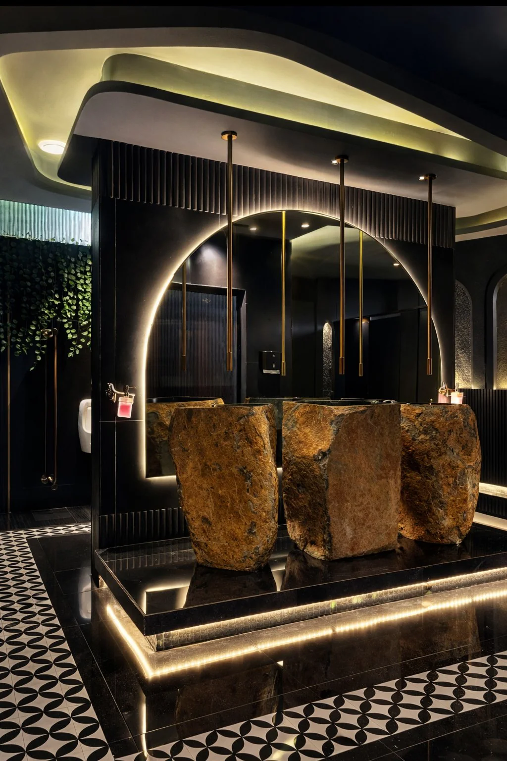 Mysore Union washroom design, Mysuru — raw-stone basins beneath a backlit arch with brass taps