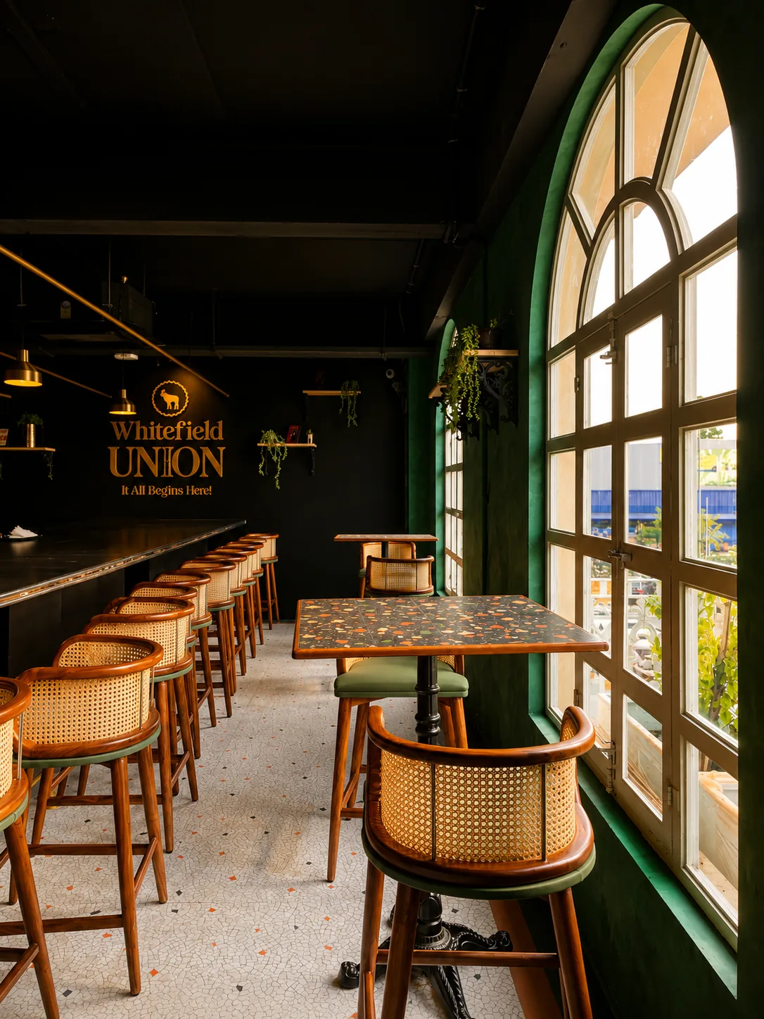 Whitefield Union, Bangalore — cane bar stools along the counter beside tall arched windows in green